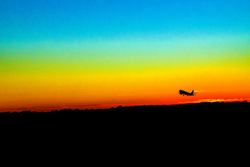 takeoff of an airplane at sunset red sun blue sky silhouettes of buildings