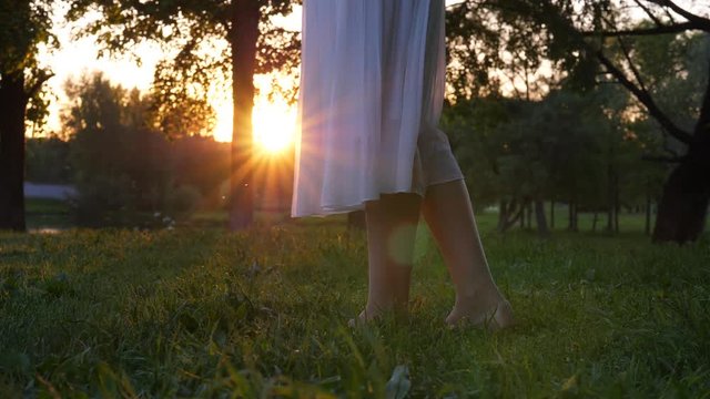Sun shine through transparent white flying skirt, woman legs close up