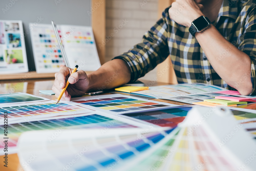 Aufkleber Young creative Graphic designer using graphics tablet to choosing Color swatch samples chart for selection coloring with work tools and accessories at workplace