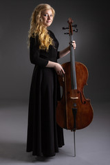 Young blond woman with cello on a dark background.