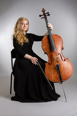 Young blond woman with a cello on a light background.