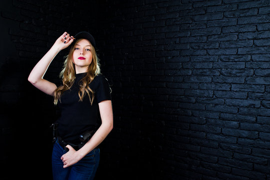 FBI Female Agent In Cap And With Gun At Studio Against Dark Brick Wall.