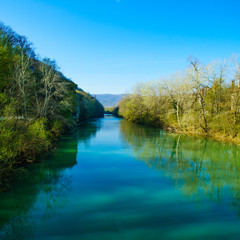 Fototapeta na wymiar Blue river flowing across green forest