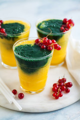 two colored fresh smoothies in glasses with fresh berries. orange banana juice with spirulina powder. detox breakfast. healthy eating