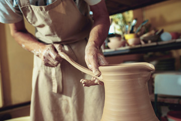 Creating a jar or vase of white clay close-up. Master crock. Man hands making clay jug macro.
