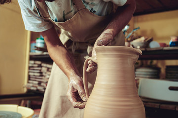 Creating a jar or vase of white clay close-up. Master crock. Man hands making clay jug macro.