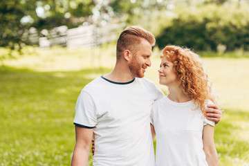 happy couple embracing and smiling each other at park