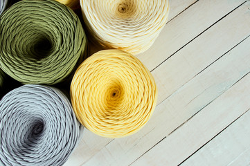 coils of colored knitted yarn on a white wooden background