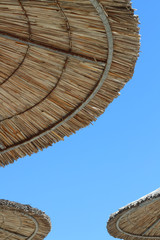 Summer lifestyle.Parasols made of cane - sunprotection. Beach time and vacation concept. Travel destination. Minimal style