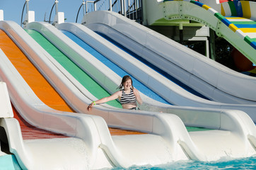 Woman sliding down on water-slide in aqua park.