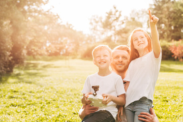 happy father with cute little kids playing with drone together at park