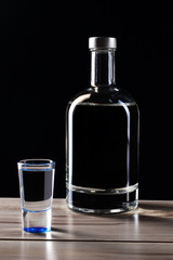bottle of vodka with a glass on a black background