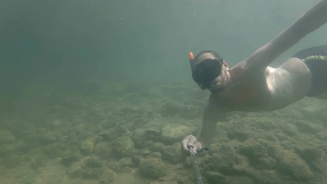 a man dives and makes a selfie under water. waving his hand to you