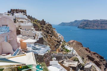 Fototapeta na wymiar Tiny little white houses, hotels and long stairway to the harbour in the Oia village at Santorini, Greece.
