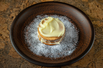 Cookies smeared with custard cream on a dark plate against a dark background
