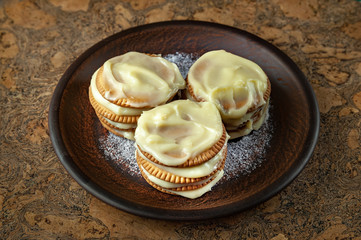 Cookies smeared with custard cream on a dark plate against a dark background