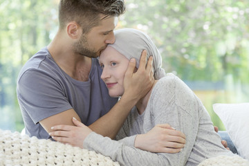 Man kissing his sick girlfriend on the forehead