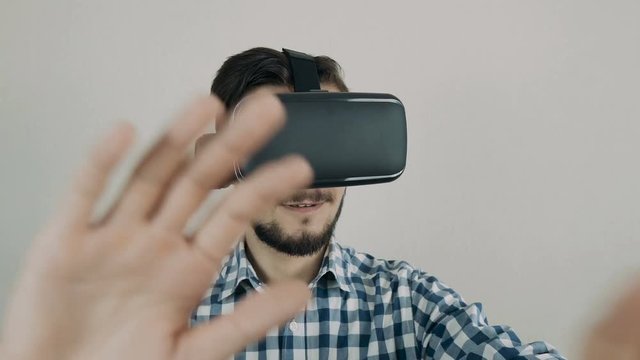 Close up shot of a young bearded man wearing virtual reality glasses - surfing net via virtual reality interface.