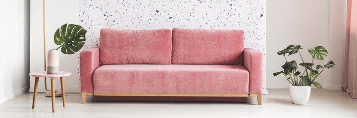 Pink velvet sofa in real photo of bright living room interior with lastrico pattern wall and...