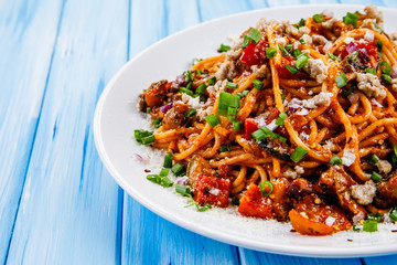 Pasta with meat and tomato sauce on wooden table