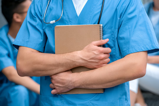 cropped image of medical student standing with notebook