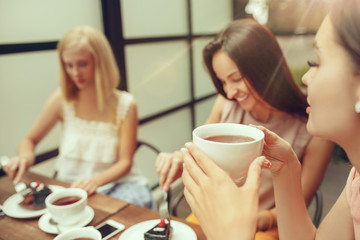 Two girl friends spend time together drinking coffee in the cafe, having breakfast and dessert.