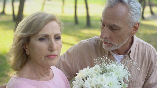 Man apologizes to woman and gives flowers to her, crisis in relations, jealousy