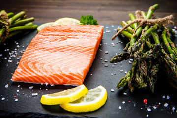 Fresh raw salmon fish served on black stone on wooden table