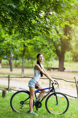 Fototapeta na wymiar Teen girl with bicycle in a park.