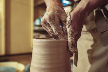 Creating a jar or vase of white clay close-up. Master crock. Man hands making clay jug macro.