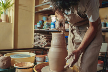Creating a jar or vase of white clay close-up. Master crock. Man hands making clay jug macro.