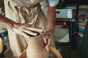 Creating a jar or vase of white clay close-up. Master crock. Man hands making clay jug macro.