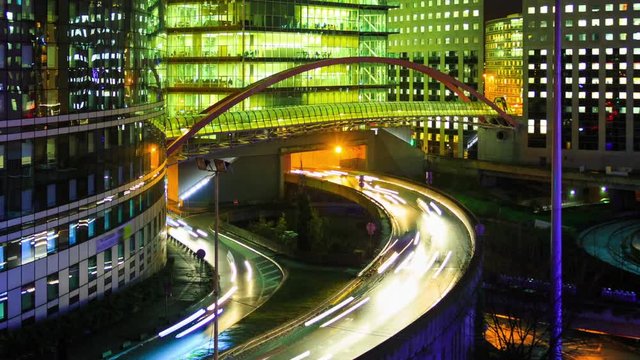 Time lapse of Paris modern buildings, dynamic urban street traffic, car lights in business district La Defense. Night cityscape with glass facade skyscrapers. Evening jam, economics, finance concept