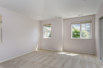 Fototapeta premium Empty sun filled bedroom with carpet floor.