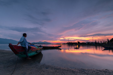 Sunset on Lap An lagoon and Lang Co bay with colorful clouds and a man looking away. Lang Co Bay is one of the most famous and beautiful bays of the world. HUE - VIETNAM date 29/04/2018