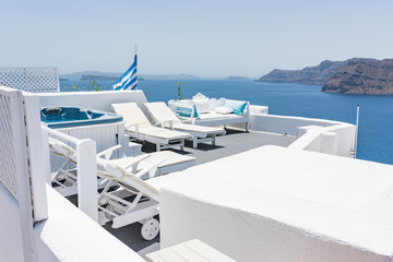 Fototapeta premium Cozy sunbeds with tiny swimming pool on top of the Oia village at Santorini, Greece.