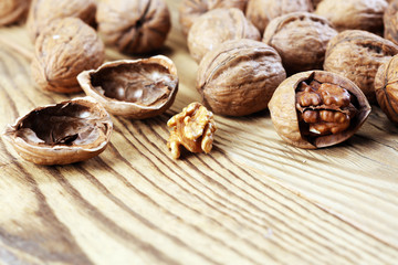 Fototapeta na wymiar Walnut kernels and whole walnuts on rustic old table.