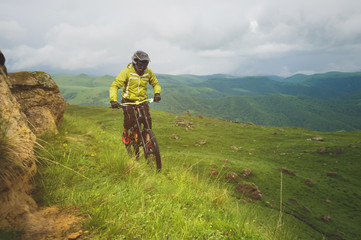 A man in a mountain helmet riding a mountain bike rides around the beautiful nature in cloudy weather. downhill