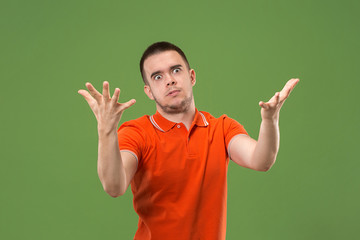 Beautiful male half-length portrait isolated on green studio backgroud. The young emotional surprised man