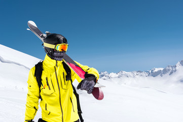 Skier standing on a slope. Man in a light suit, the helmet and mask in skiing is to ski. In the...