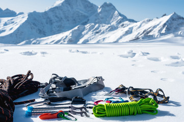 Winter set of equipment of an ice climber with carabiner wounds and a camp thermos against the background of snow-capped mountains . Copy space for the designer