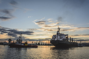 Obraz premium Tug boat entering the harbor with big cargo boat.