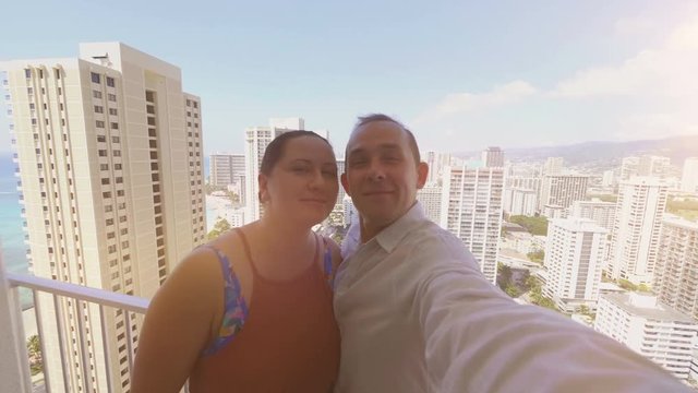 Professional video of happy couple taking a selfie and kissing in Honolulu Hawaii in 4k slow motion 60fps