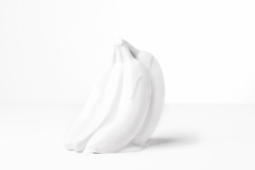 Bananas covered in a white dripping substance, shot against a white background. 