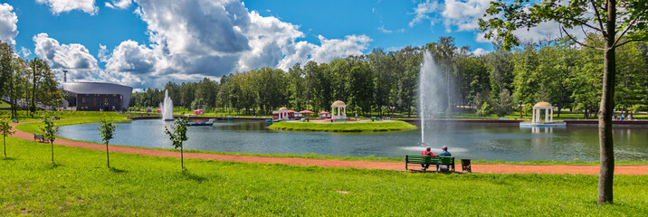 clear transparent sky slightly tightened by clouds on the background of people resting on a bench by the pond