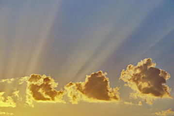 Lonely clouds in the sky bathe in the rays of the setting sun. Beautiful picture of a summer warm evening.