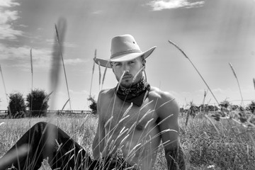 Sexy, handsome, hunky cowboy with hat open shirt and pecs looks at camera