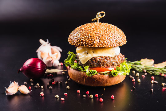 Juicy delicious burger with spices on a black background