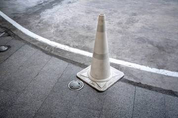 White traffic cone on concrete road standing by walkway