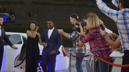 Famous African-American man and woman walking out of limo and posing for shoots and giving autographs on red carpet of celebrity event